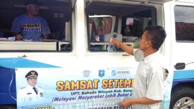 Seorang WPL Menyerahkkan Uang Pembayaran Pajak Kendaraan Bermotor Roda 2 Kepada Petugas Samsat Sungailiat di Kegiatan Samsat Setempoh, Pasar Malam Kenangan Sungailiat Kabupaten Bangka, Senin, 17 Februari 2020